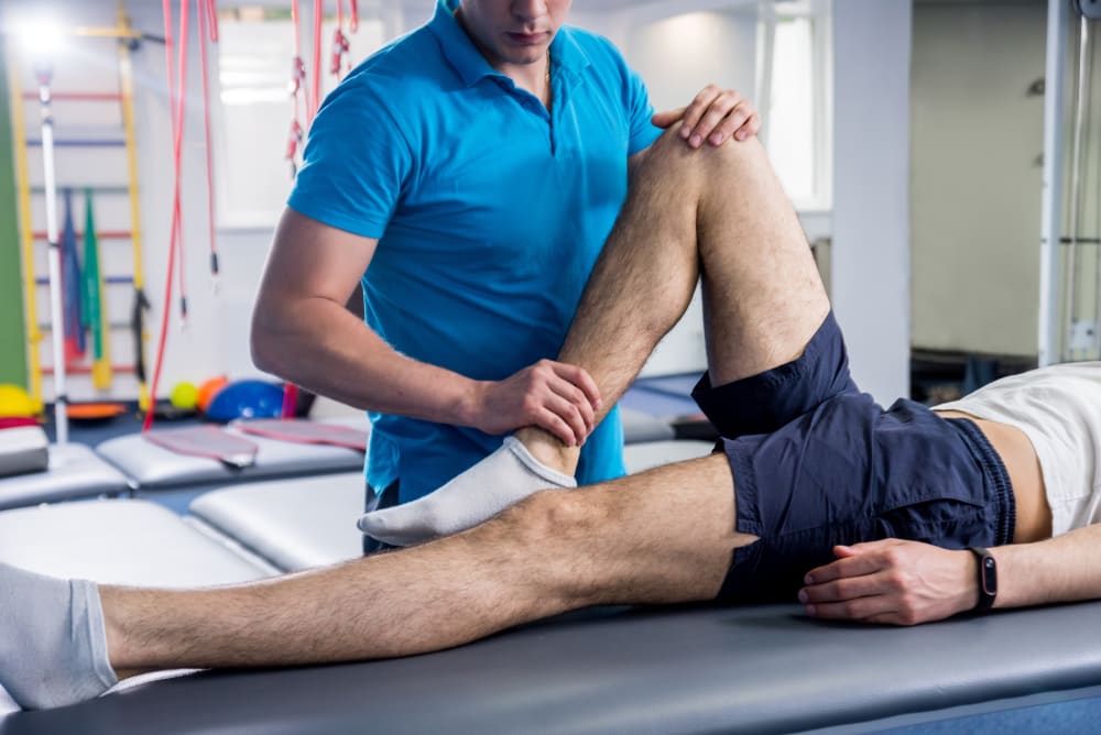 Physiotherapist working with young male patient in rehabilitation center